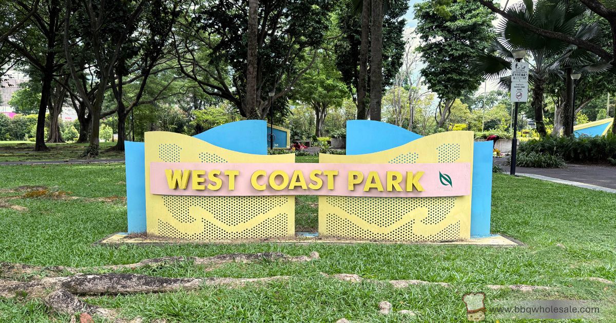 Colorful West Coast Park entrance sign surrounded by greenery, highlighting BBQ pit facilities and family-friendly activities in Singapore